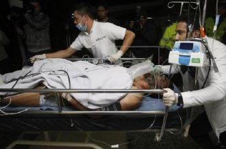Foto: EFE: Momento da chegada de Alan Ruschel ao hospital, ainda na maca e com ferimentos. Jogador foi o primeiro a ser resgatado.