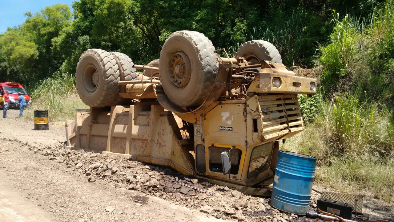 Caminhão tomba em pedreira e motorista fica preso na cabine