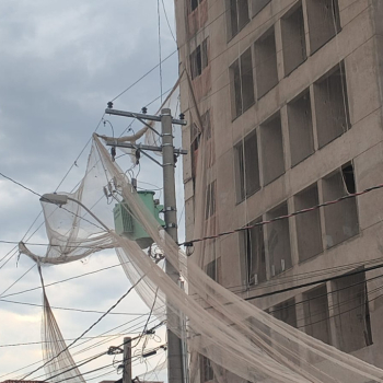 Ventos soltam tela de proteção de obra, que fica presa à rede elétrica em Botucatu