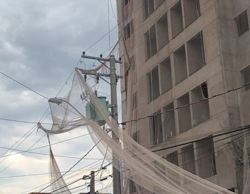 Ventos soltam tela de proteção de obra, que fica presa à rede elétrica em Botucatu