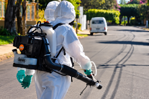 Operador de nebulização em rua ensolarada dengue